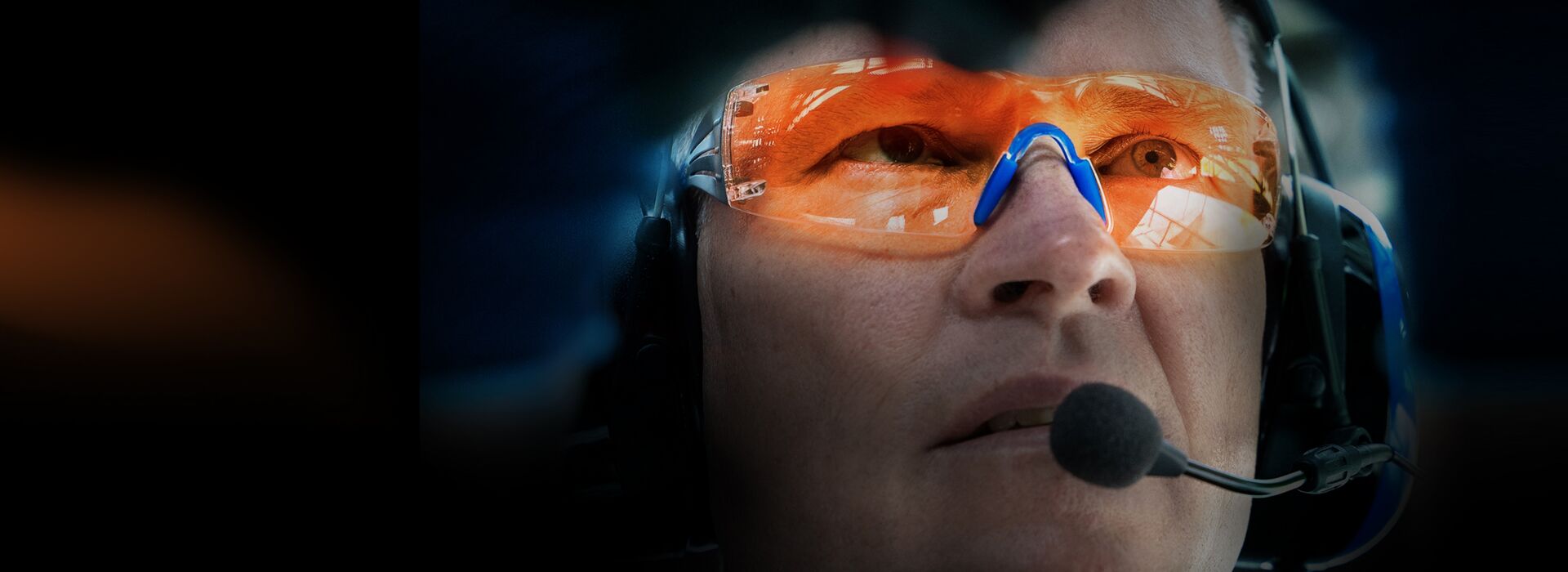 Ein fokussierter Mitarbeiter mit orangener Schutzbrille bei der Arbeit