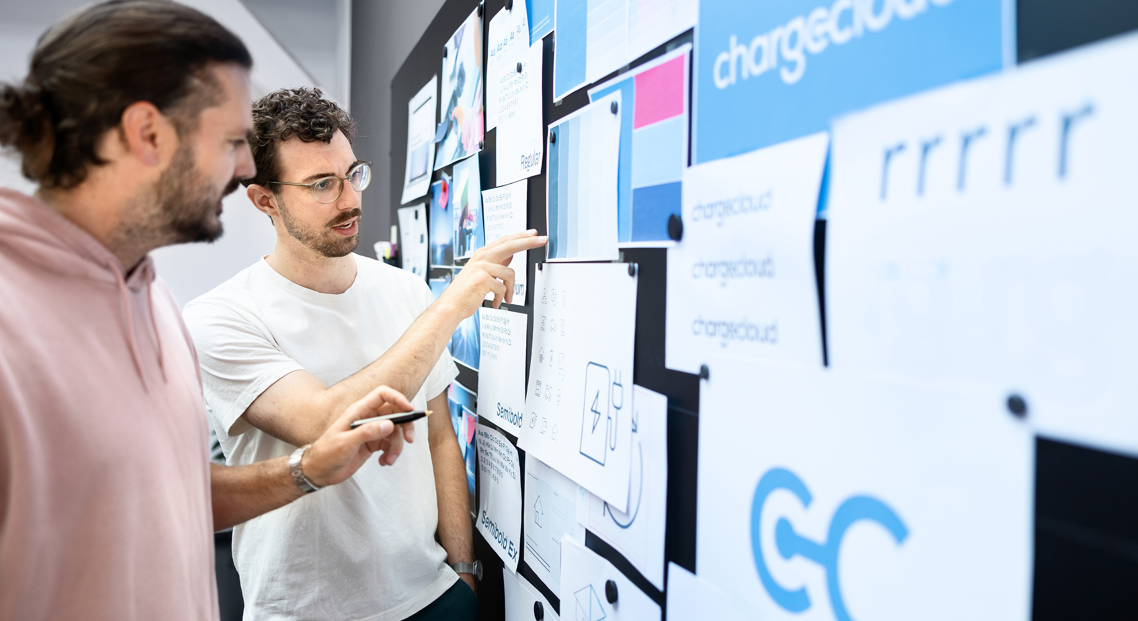 Zwei Männer aus der Brainfactory arbeiten gemeinsam an den visuellen Elementen der chargecloud-Marke.
