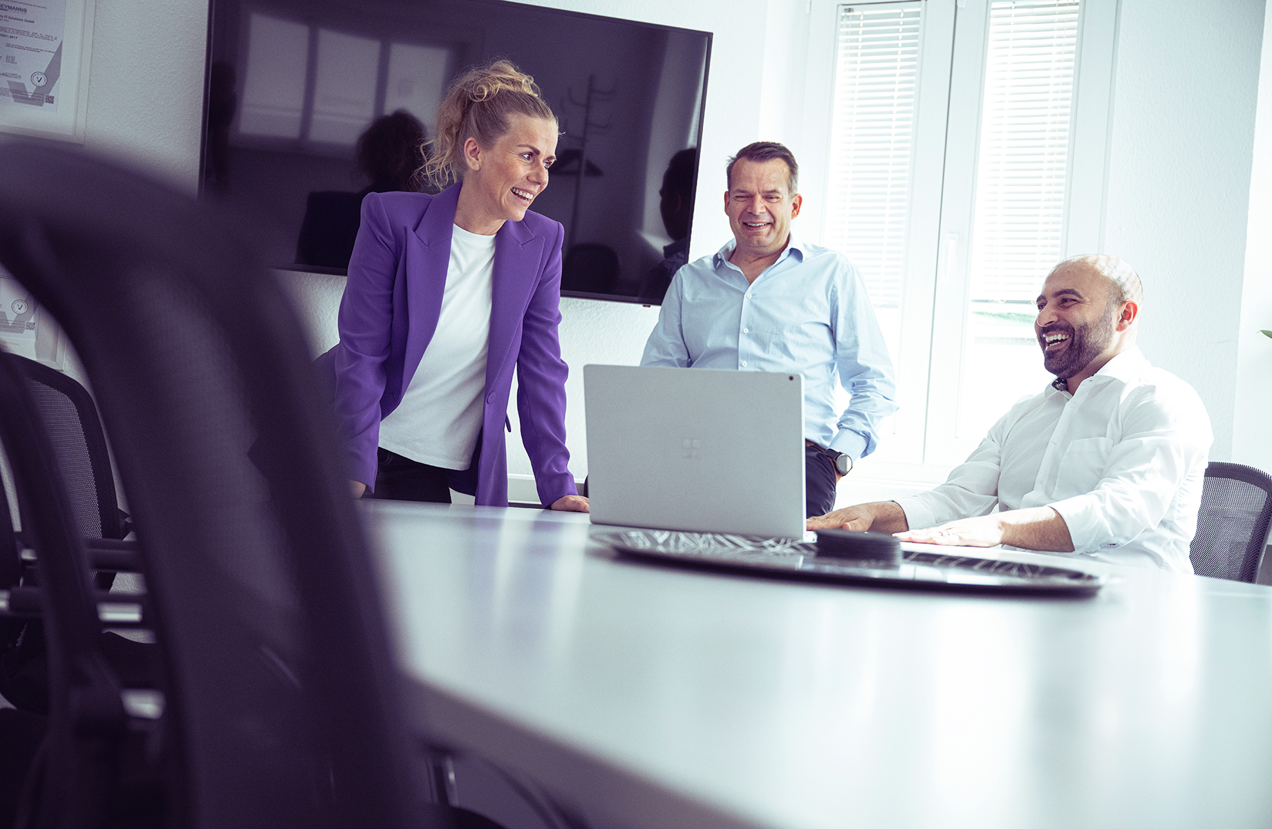 Meetingsituation: Herr Heymanns im Gespräch mit zwei Mitarbeitenden, lächelnd